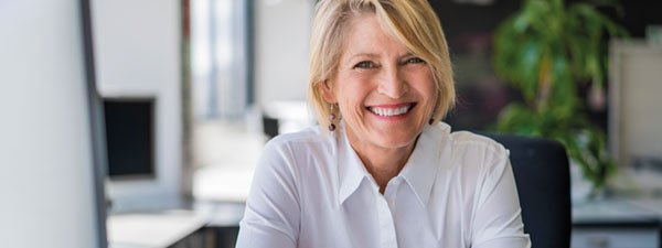 Happy mature businesswoman sitting at desk